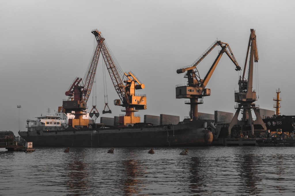 Cargo ship docked at a port with large cranes, showcasing industrial logistics operations.